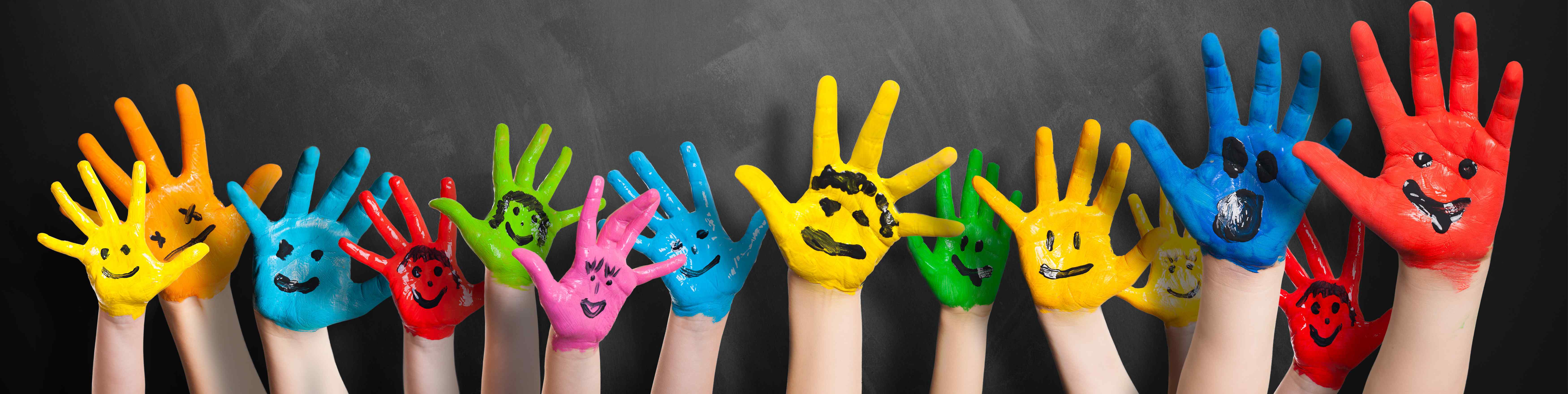 Image of children's hands covered in paint with smiley faces; Shutterstock.